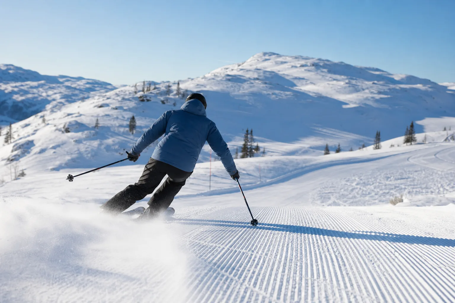 Alpinskidåkare svänger i nypreparerad pist en klar vinterdag