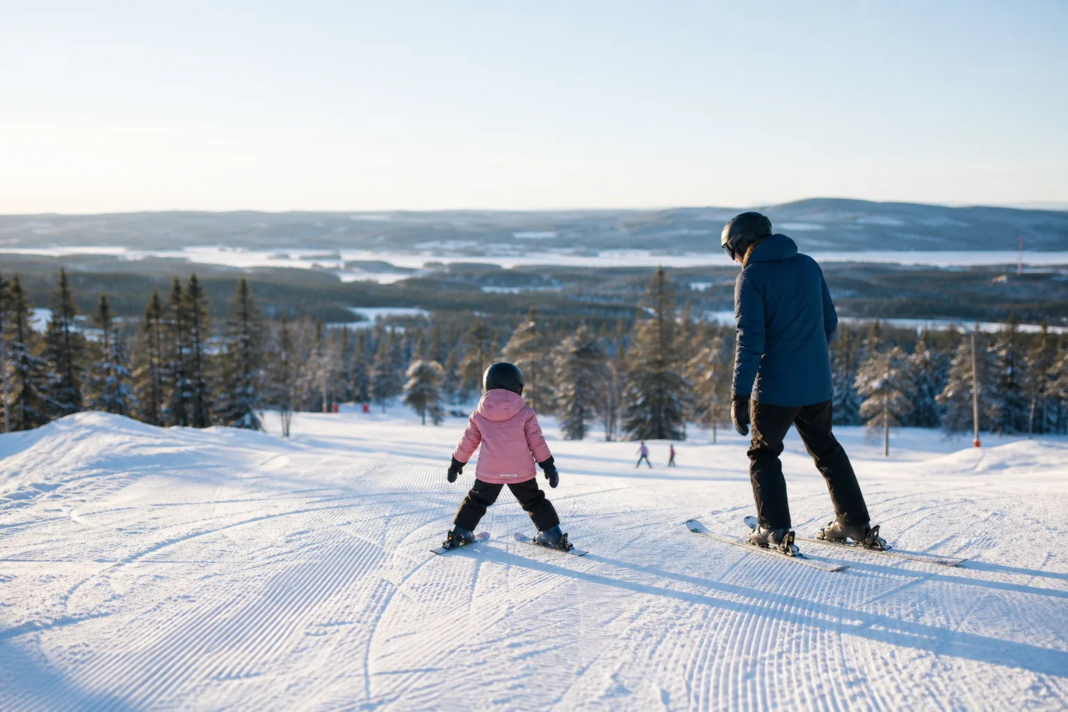 Nybörjarbarn provar sina första skidor på en lätt slänt med en förälder bredvid