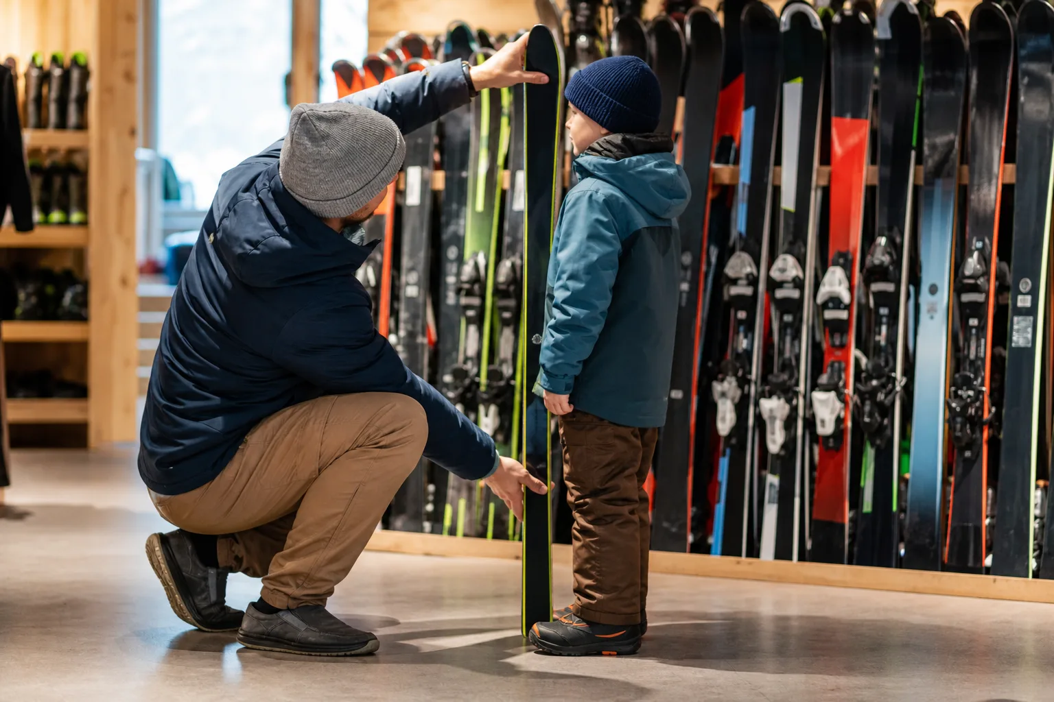 Förälder mäter ett barns kroppslängd mot en skida inför köp