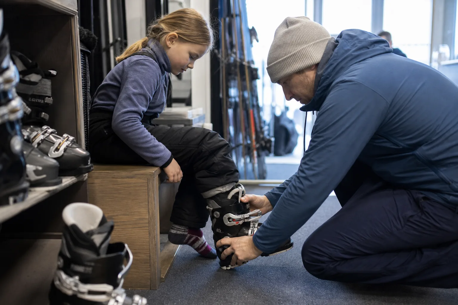 Barn provar skidpjäxor tillsammans med en förälder i en skidbutik