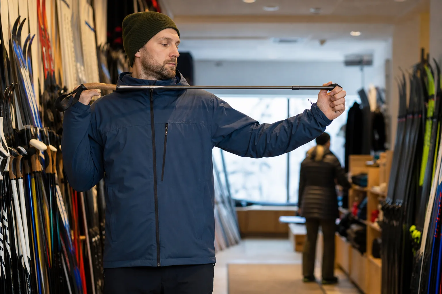 Längdskidåkare mäter stavlängd mot axelhöjd i en skidbutik