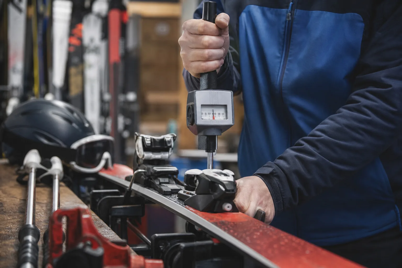 Skidteknikers hand justerar en bindnings inställning med kalibrerat verktyg i en verkstad